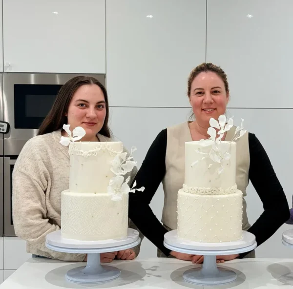 Deux p&acirc;tissi&egrave;res pr&eacute;sentent leurs wedding cakes blancs &agrave; deux &eacute;tages, d&eacute;cor&eacute;s de fleurs en sucre
