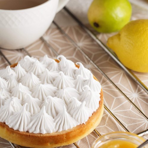 Beautiful freshly made white lemon meringue tart on plate. Lemon meringue pie still life composition. Food photography.